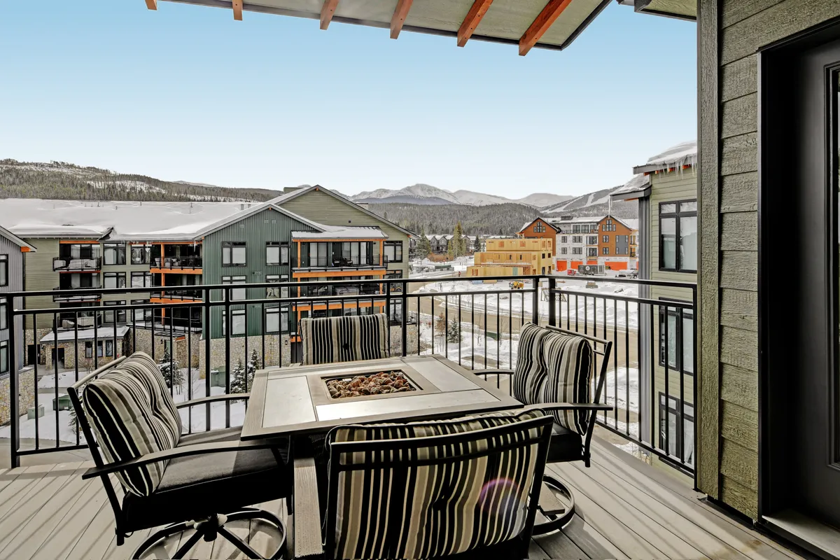 A wider view of an outdoor balcony area with mountain views, a fire pit, and ample seating. The landscape showcases both the connection to nature and the tranquility of the space, inviting residents to unwind and appreciate the scenic surroundings.