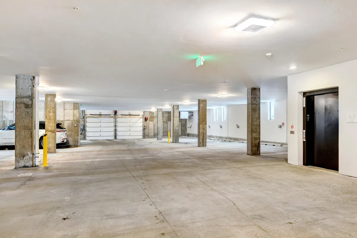 A clean, modern heated underground garage is depicted, offering ample parking spaces, bicycle storage, and easy access with an elevator entrance. The lighting and finishes emphasize both security and convenience.
