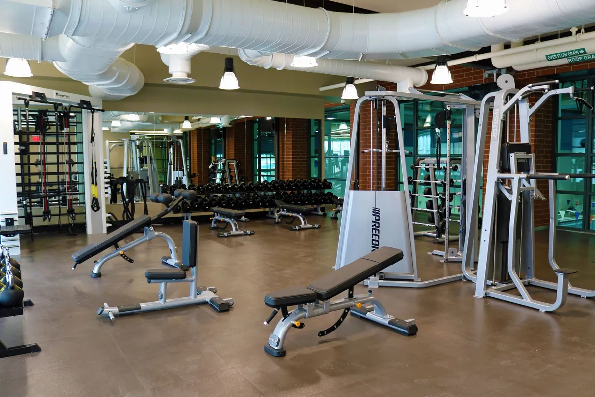 This image showcases a well-equipped fitness center with weightlifting benches, dumbbell racks, and modern exercise machines. The space is bright and motivational, encouraging guests to stay active indoors, regardless of the season.